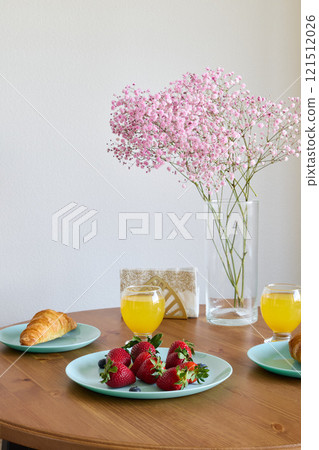 A beautifully arranged elegant breakfast table featuring fresh strawberries and a flaky croissant 121512026