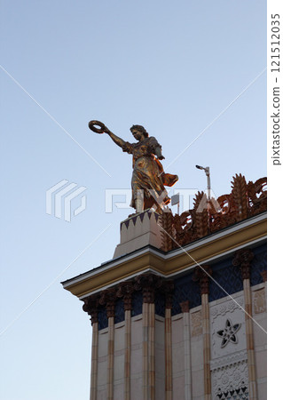 A Majestic Golden Statue Standing Tall, Overlooking the Beautiful City Skyline at Sunset 121512035