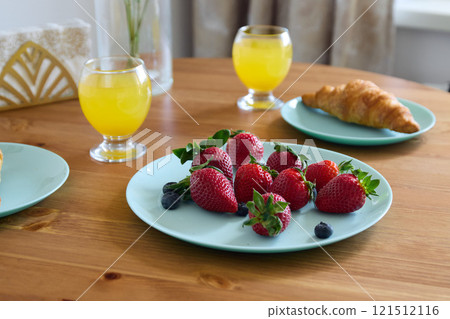 Enjoy a Fresh Fruit Breakfast featuring Juices and a Croissant displayed elegantly on a Wooden Table Enjoy a Fresh Fruit Breakfast featuring Juices and a Croissant displayed elegantly on a Wooden Table 121512116