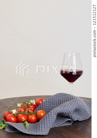A Beautifully Arranged Red Wine Glass along with Fresh Cherry Tomatoes on a Dark Wooden Table 121512127