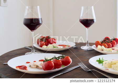 An Elegant Dinner Table Setting Featuring Wine, Colorful Tomatoes, and Fine Tableware 121512174