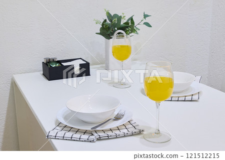 An Elegant Dining Table Setup with Bright Yellow Drinks and Fresh Greenery Accents 121512215