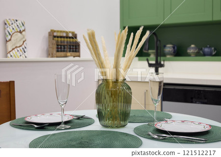 An Elegant Dining Setup with Green Accents and a Decorative Vase to Enhance Ambiance 121512217