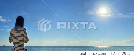 一位年輕女子俯瞰著在陽光下閃閃發光的大海 121512902