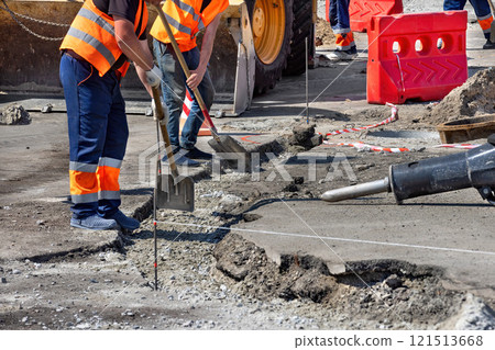 Construction workers repairing pavement in a busy urban area during daylight hours 121513668