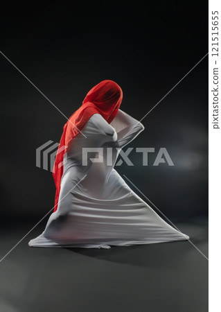 Movement of fabric and color creates abstract art in a dark setting 121515655