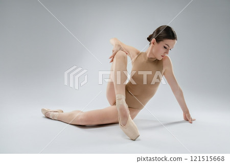 Ballet dancer performing a flexible pose in studio with gray backdrop 121515668