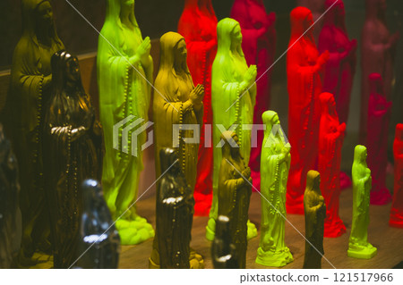 Multicolored figurines of Virgin Mary. Pop Art decorative products. Religion, catholic church, faith concept. Colorful souvenirs in a store window. 121517966