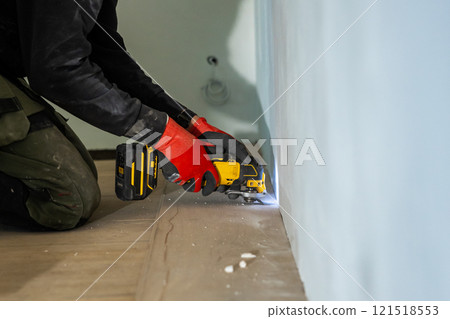 Person Using Yellow Power Tool on Light Blue Wall Indoors 121518553