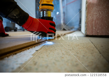Close Up of Worker Using Power Tool on Wooden Floor Indoors 121518558
