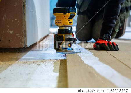 Close Up of Hands Operating Yellow and Black Power Tool on Wood 121518567