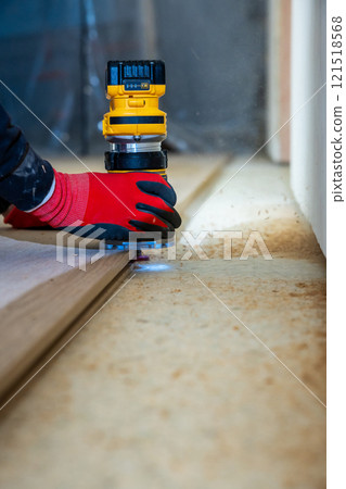 Person Using Yellow Router on Wood with Red Gloves Indoors 121518568