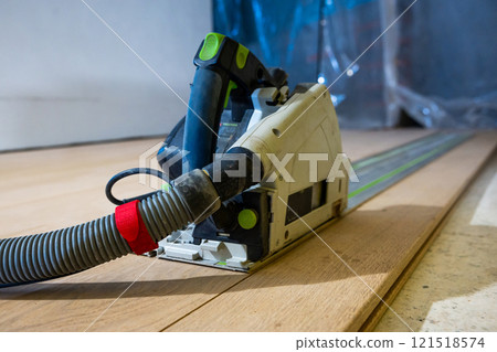 Close Up of Track Saw with Dust Hose on Wooden Floor 121518574