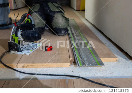 Person Using Circular Saw and Guide Rail for Flooring Installation Person Using Circular Saw and Guide Rail for Flooring Installation 121518575