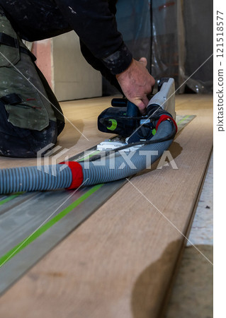Person Using Track Saw with Vacuum Hose in Indoor Construction Setting Person Using Track Saw with Vacuum Hose in Indoor Construction Setting 121518577
