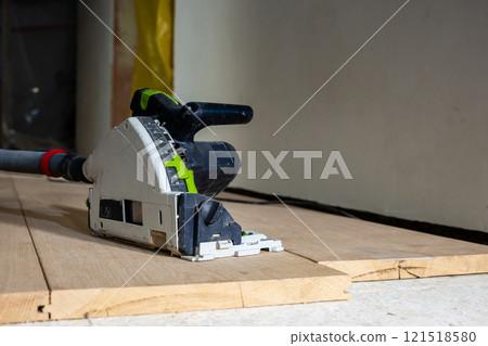 Track Saw with Dust Extraction Hose on Wooden Planks Indoors Track Saw with Dust Extraction Hose on Wooden Planks Indoors 121518580