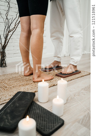 A girl helps a man to stand on nails. Sadhu board. Pleasant atmosphere white candles relaxation. Concept on healthy lifestyle. 121518961