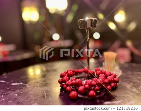 Beautiful red beads as a decor on a table in cafe on Christmas holidays with night light behind Beautiful red beads as a decor on a table in cafe on Christmas holidays with night light behind 121519210