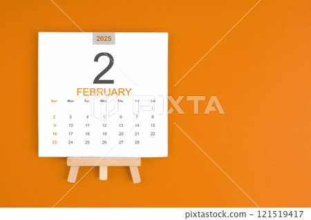 Calendar page for February 2025 with wood easel on orange background. 121519417