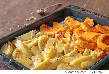 Sliced potatoes and pumpkin with pine nuts and spices on baking tray. Raw vegetables for baking. Healthy food in kitchen at home. Natural farm local products. Sliced potatoes and pumpkin with pine nuts and spices on baking tray. Raw vegetables for baking. Healthy food in kitchen at home. Natural farm local products. 121519755