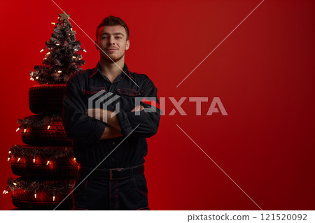 Christmas tree made of car tires and man on red background with copy space 121520092