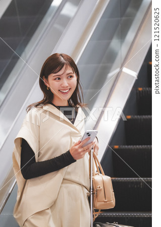 A woman arrives at the airport and descends the escalator A woman arrives at the airport and descends the escalator 121520625