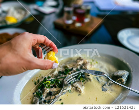 Fried Golden trout fish with lemon and herbs in a white plate on a wooden table at the restaurant in Ukraine Fried Golden trout fish with lemon and herbs in a white plate on a wooden table at the restaurant in Ukraine 121521425