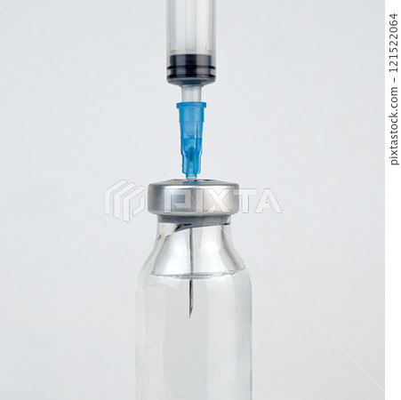 A syringe is inserted into a vial, drawing liquid into the syringe for use A syringe is inserted into a vial, drawing liquid into the syringe for use 121522064