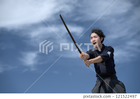 A young man screaming and holding a wooden sword 121522497