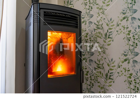 Horizontal photo of a very dirty pellet stove inside a living room of a house. Renewable energy source. Biomass in the form of pellets. 121522724