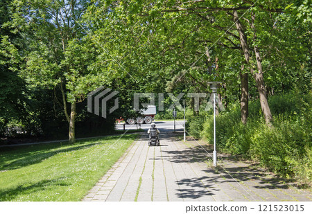 A man in a wheelchair is driving along the road to the parks. 121523015