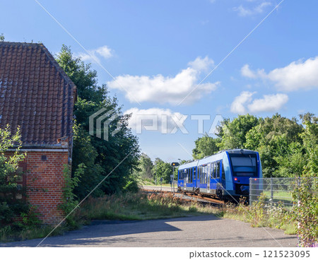 A Blue train rides through the countryside. 121523095
