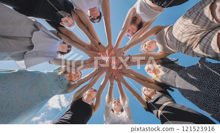 High school students join hands in a circle, bonding over summer break and the strength of their friendship under a sunny sky 121523916
