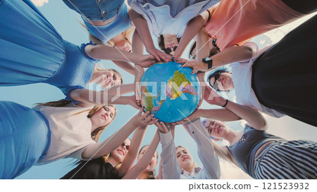 Earth conservation concept. 10 girls and boys surround the rotating earth globe with their palms A view in motion. 121523932
