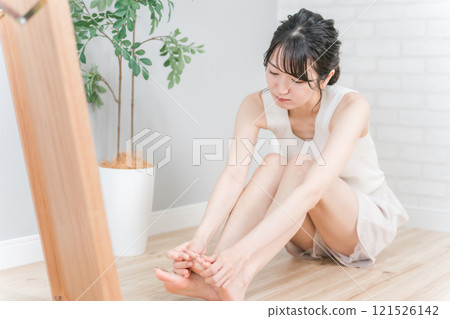Young Asian woman worried about her toes (bunion, ingrown toenails, athlete's foot, soles of the feet, pedicure) 121526142