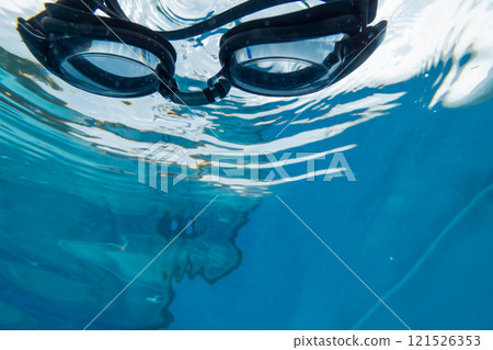 伸手撿起泳池裡脫落的護目鏡 伸手撿起泳池裡脫落的護目鏡 121526353
