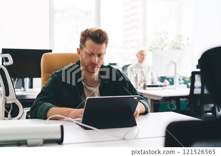 Focused man working on laptop in office Focused man working on laptop in office 121526565