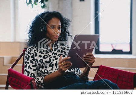 Creative Black female content strategist reviewing social media analytics on tablet, in a modern workspace, reflecting engagement and strategic thinking Creative Black female content strategist reviewing social media analytics on tablet, in a modern workspace, reflecting engagement and strategic thinking 121526602