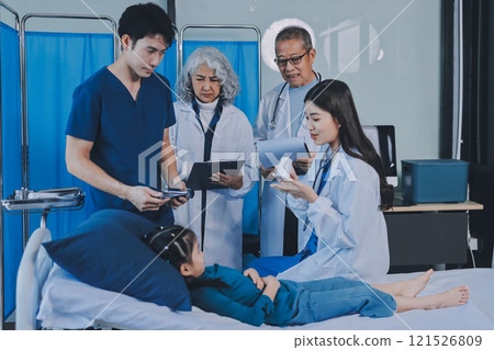 A team of doctors and nurses are working to treat a female patient in the patient's room. A team of doctors and nurses are working to treat a female patient in the patient's room. 121526809