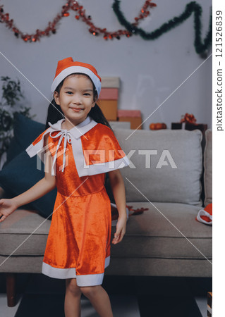 Christmas holidays concept. Happy magic little girl opens a gift box. Child is happy with a New Year's gift. The background is Christmas tree. The concept of Christmas and New Year. High quality photo 121526839