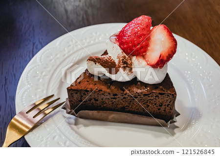 Strawberry cake on a white plate with a gold fork 121526845
