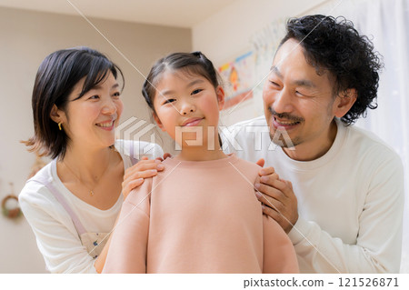 Close-up image of a family of three smiling, with the daughter looking at the camera, a cute image of the only daughter Close-up image of a family of three smiling, with the daughter looking at the camera, a cute image of the only daughter 121526871