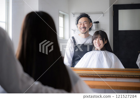 Image of a customer and a hairdresser getting their hair cut or cared for at a beauty salon 121527284