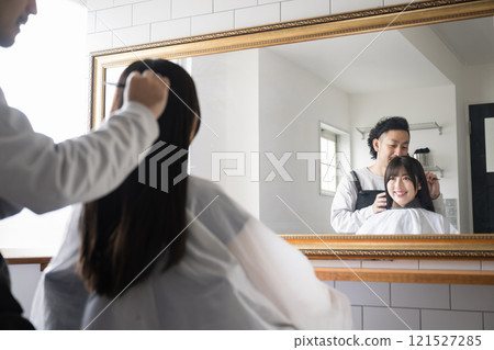 Image of a customer and a hairdresser getting their hair cut or cared for at a beauty salon 121527285