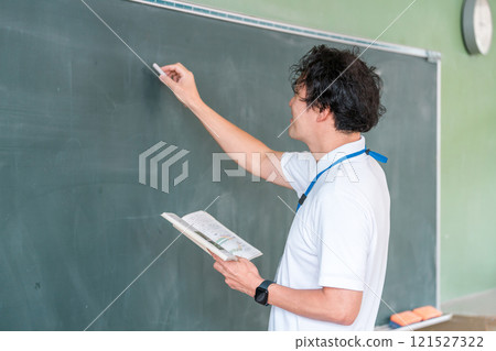 Male teacher giving a lesson in front of the blackboard Male teacher giving a lesson in front of the blackboard 121527322