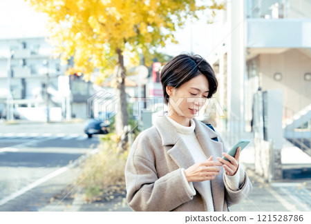 A woman looking at a smartphone outdoors 121528786