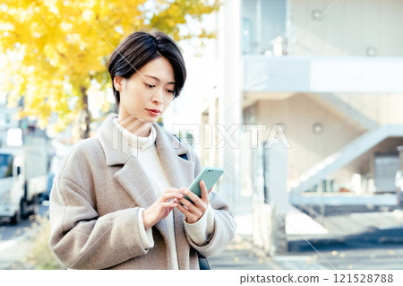A woman looking at a smartphone outdoors A woman looking at a smartphone outdoors 121528788