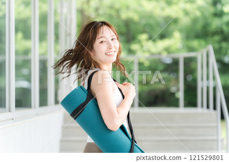 Healthy woman holding a yoga mat (yoga instructor/yogini) 121529801