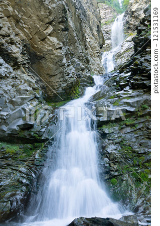 Picturesque stream of a tall waterfall in the canyon with mossy rocks. Picturesque stream of a tall waterfall in the canyon with mossy rocks. 121531169