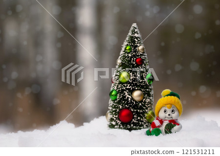 Miniature figurines of Christmas tree and a snowman in the snowy forest. Miniature figurines of Christmas tree and a snowman in the snowy forest. 121531211